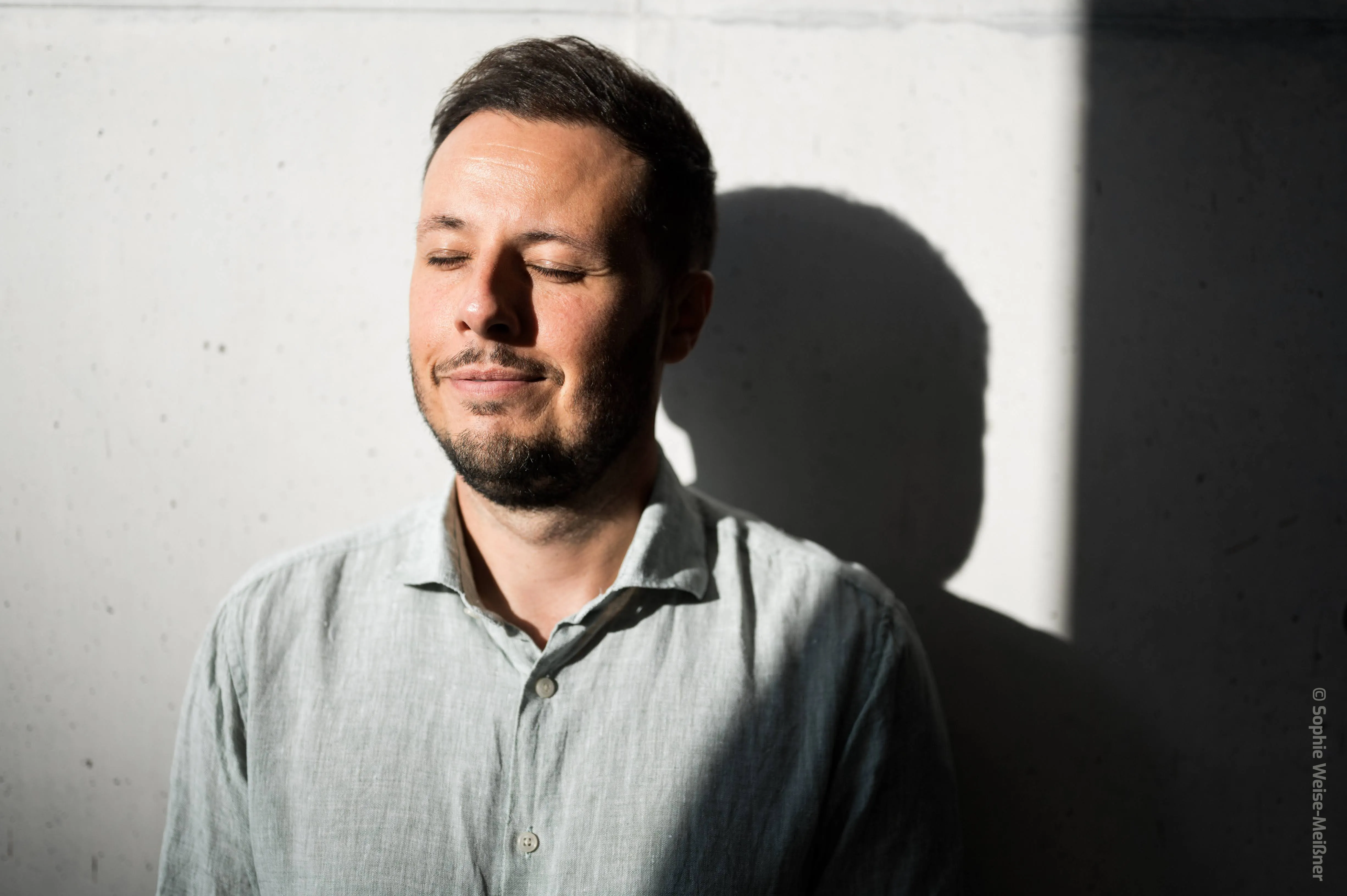 Vadim Tarek Mousa im Sonnenlicht vor einer Betonwand